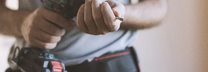 Person hält Bohrmaschine und Bohrer